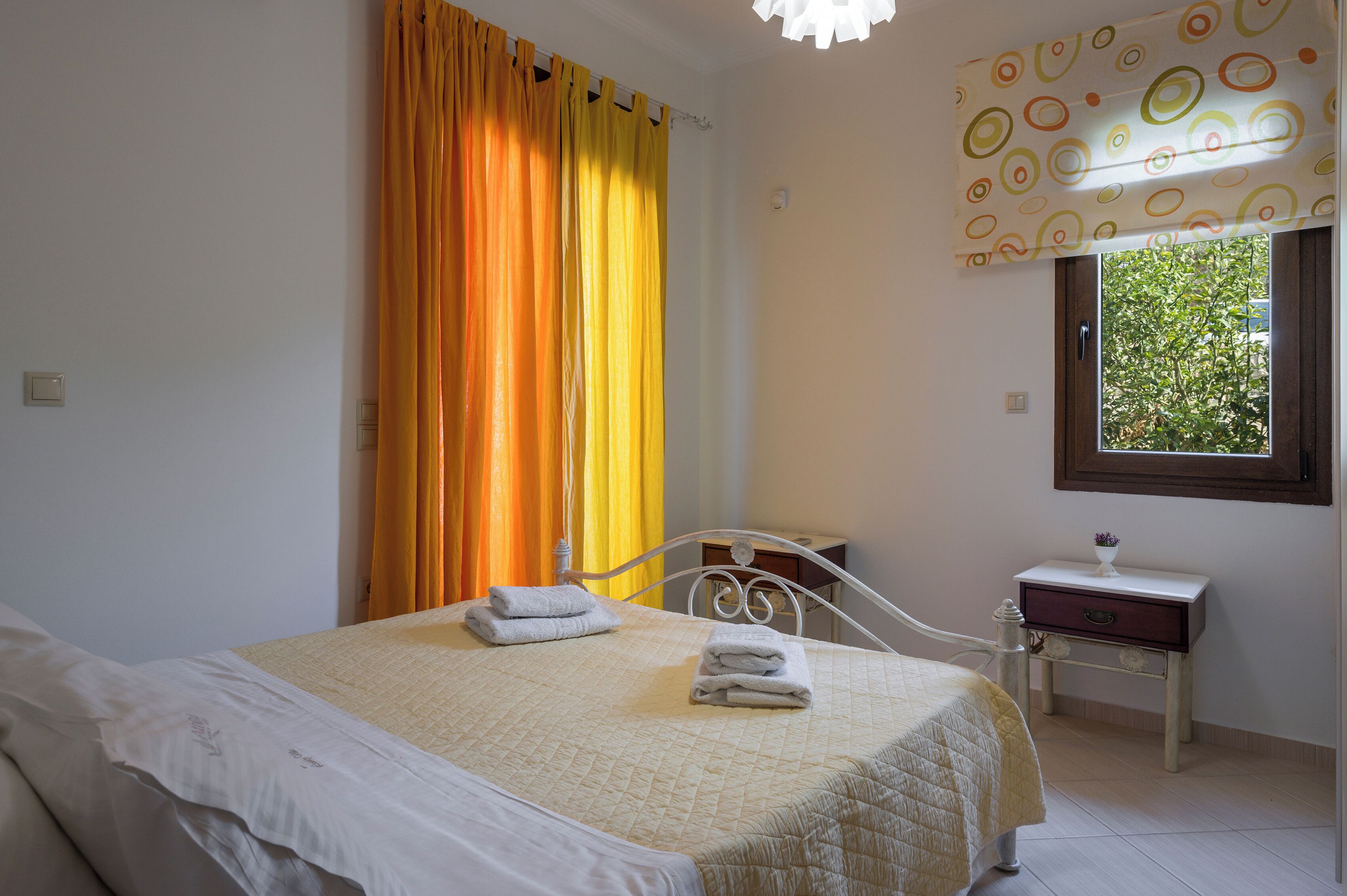 A bedroom with a bed, a nightstand, a window, and curtains.