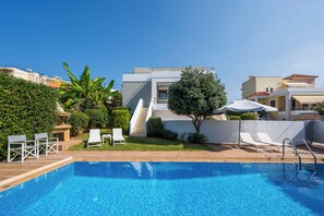 A swimming pool with lounge chairs, a small garden, and a modern building with a flat roof. - Villa Katerina (Chania)