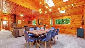 A wooden cabin interior with a dining area, sofa, and kitchen. - Charming 3BR with Hot Tub, Balcony & Wood Stove (Guerneville)