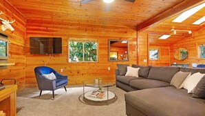 A cozy log cabin interior with a sofa, armchair, and a small coffee table. - Charming 3BR with Hot Tub, Balcony & Wood Stove (Guerneville)