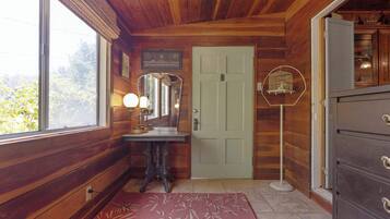 Un intérieur en bois avec une porte en bois, un miroir, une commode et une fenêtre.