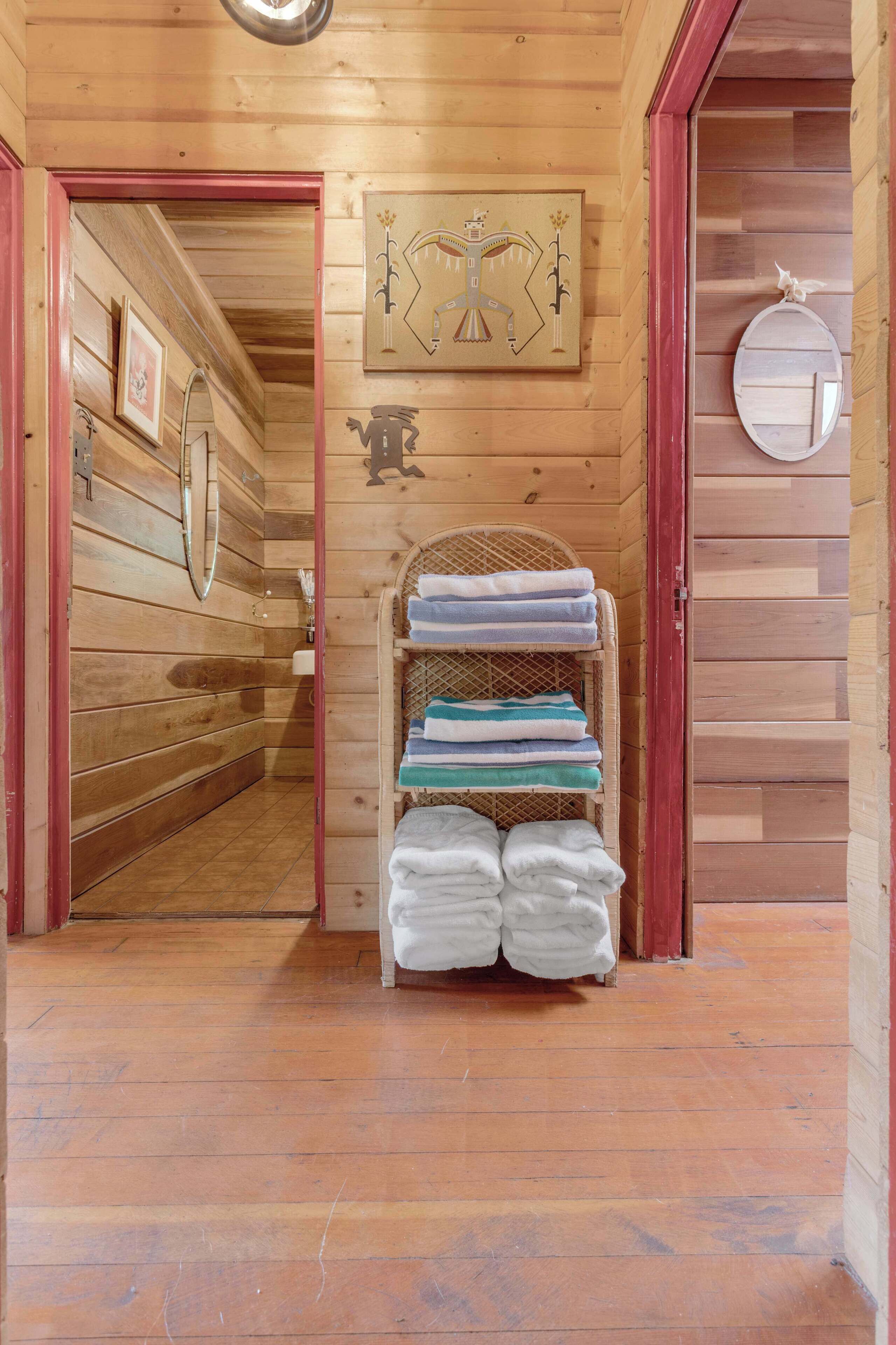 A wooden interior with a hallway leading to a bathroom. A towel rack with folded towels is visible.