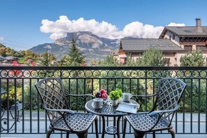 A balcony with two metal chairs, a small table, and a potted plant. - Arbois 3 Bed Balcony Plush Apartment by Telecabine (Saint-Gervais-les-Bains)