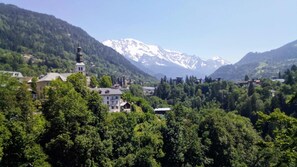 A mountainous village with a prominent church and residential buildings amidst lush greenery.