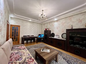 A living room with a sofa, coffee table, TV, and a cabinet. - Private Spacious Apartment close to Center, Baku (Bakı)