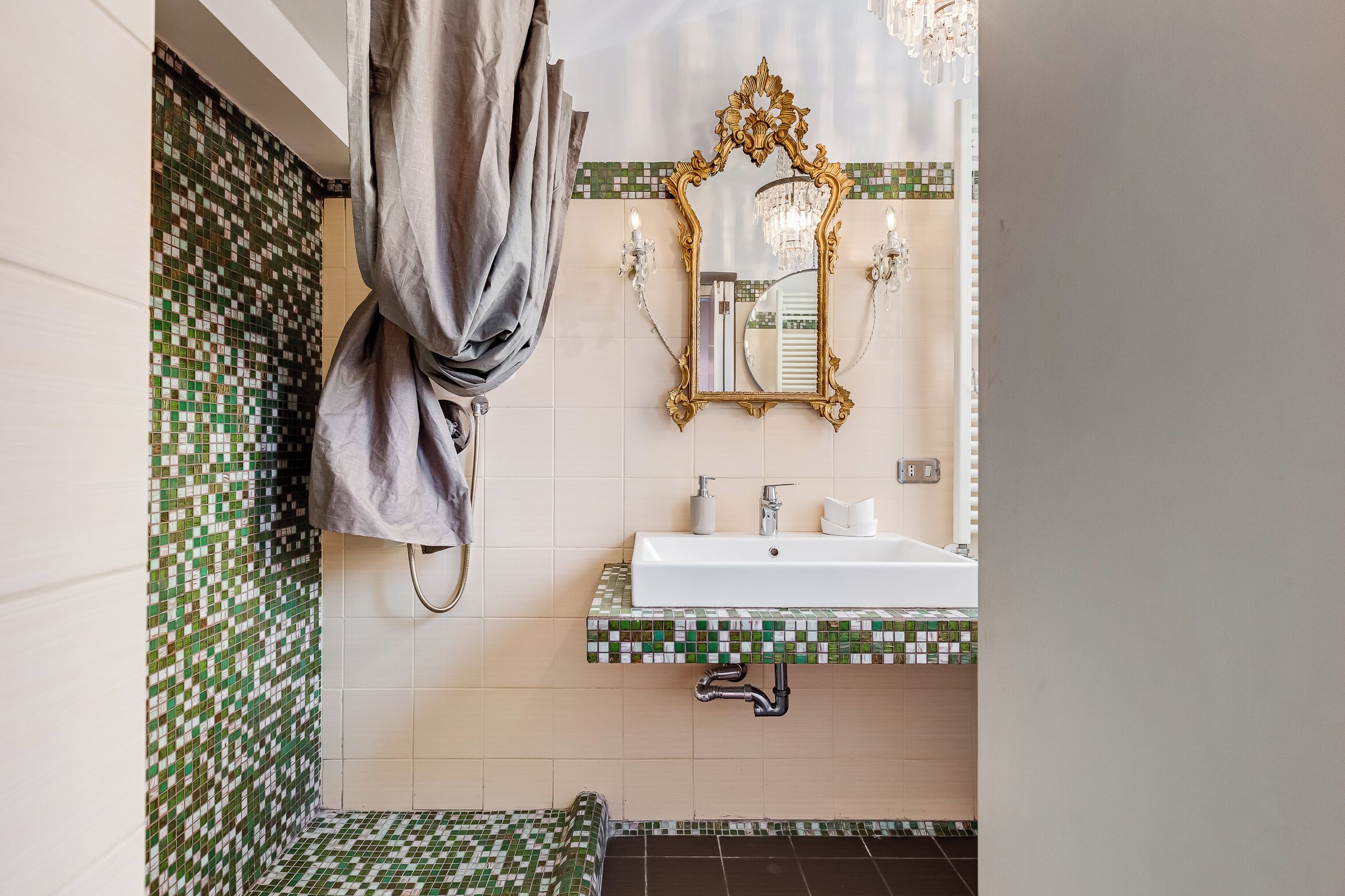 A bathroom with a sink, mirror, and shower area.