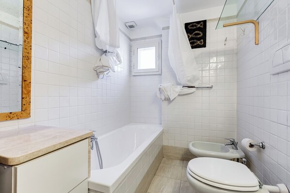 A bathroom with a bathtub, toilet, and sink, all with white fixtures.