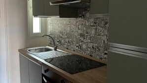 Een keuken met een roestvrijstalen spoelbak, een magnetron en een koelkast.