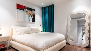 A modern bedroom with a large bed, a unique mirror, and a painting on the wall. - Luxurious Haven in Battersea  (London)