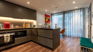 A modern kitchen with a central island, built-in appliances, and a dining area with a view of the city. - Luxurious Haven in Battersea  (London)