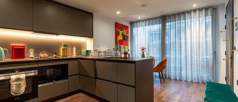 A modern kitchen with a central island, built-in appliances, and a dining area with a view of the city.