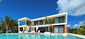 A modern two-story house with a pool, surrounded by palm trees and a clear blue sky. - Villa Solarah Turks & Caicos – 5-Bedroom Canalfront Luxury with Pool, Dock & Kayaks (Leeward Settlement)
