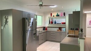 Een moderne keuken met een grote koelkast, een plafondventilator en een raam met uitzicht.