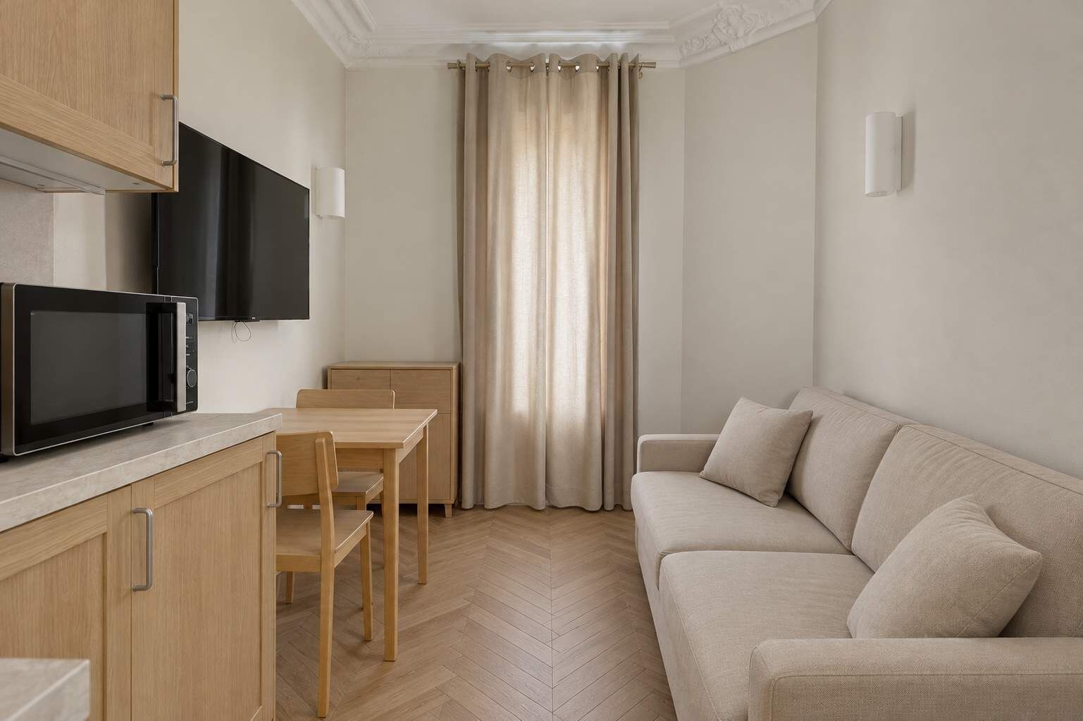 Un espacio habitable compacto con kitchenette, comedor y zona de estar.