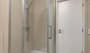 Ducha envuelta en vidrio con cabezal de ducha de mano y llave de pared.