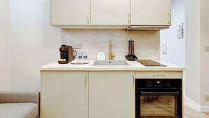 A compact kitchen with a built-in oven, a coffee maker, and a sink.