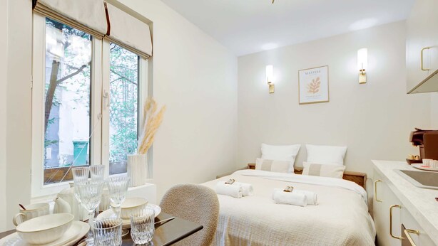 A hotel room with a bed, bedside table, and a window with curtains.