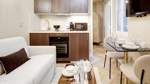 Un espacio habitable compacto con kitchenette, comedor y sofá.