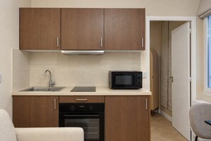 A compact kitchenette with wooden cabinets, a microwave, a dishwasher, and a sink. - Charmant cocon à Belleville • Paris • 3 personnes (Paris)