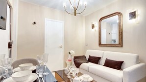 Una sala de estar moderna con un sofá blanco, una mesa de centro de vidrio y un comedor con platos y vasos.