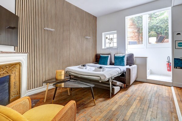 Un dormitorio moderno con cama, mesita de noche y ventana con vistas a zonas verdes.