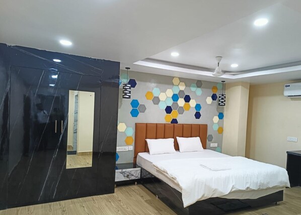 A modern bedroom with a bed, a mirror, and a wall with hexagonal patterns. - THE ODYSSEY INN (Puri)