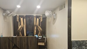 Ein moderner Empfangstresen, zwei Wandventilatoren und eine Wanduhr.