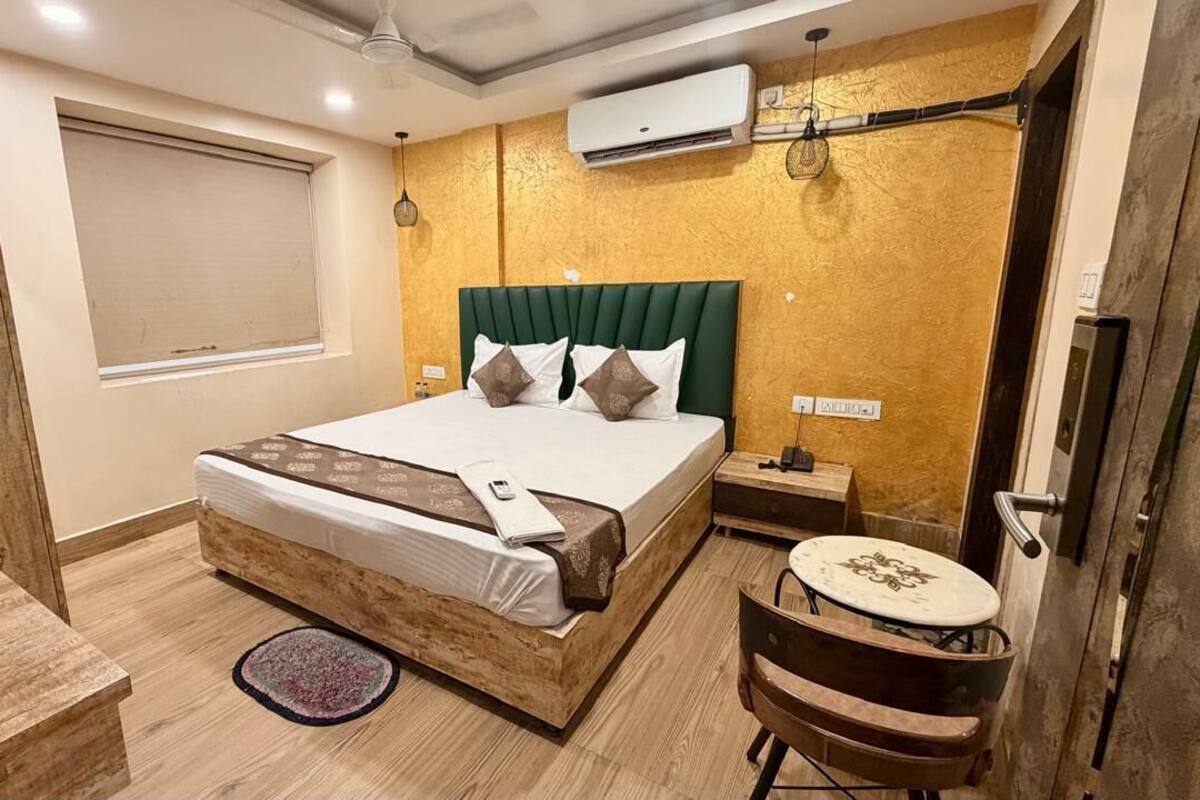 A modern bedroom with a wooden bed, a small round table, a bedside lamp, and a window with a view.