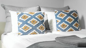 A bed with two pillows featuring a blue and yellow diamond pattern. - MARGI Lotus Apartment (Szczecin)