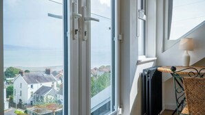 Une pièce dotée d’une grande fenêtre donnant sur un quartier résidentiel et la mer.