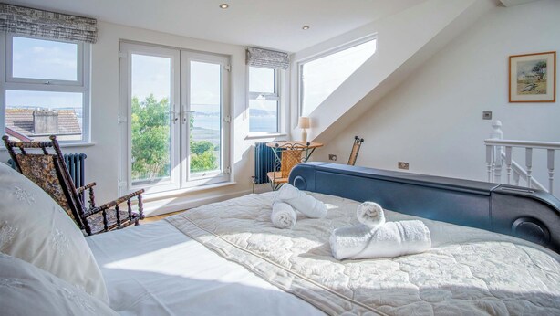 Une chambre à coucher avec un grand lit, une vue sur l’extérieur et une fenêtre donnant sur la mer.