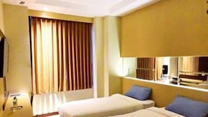 A hotel room with two beds, a desk, a chair, a television, and a window with curtains. - MP Hotel Kelapa Gading (Jakarta)