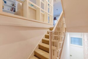A staircase with a white railing, a door with a window, and a bookshelf with books.