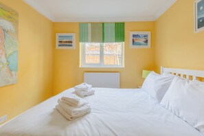 Une chambre d’hôtel avec un lit, une fenêtre donnant sur un beau paysage et des œuvres d’art accrochées aux murs.