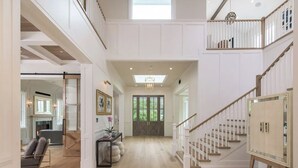 A spacious interior with a wooden floor, a staircase, and a view of the outdoors through a large door.