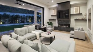 A modern living room with a large sofa set, a fireplace, and a TV mounted on the wall.