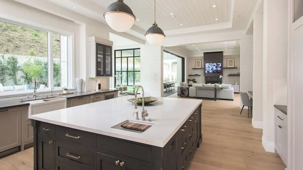 A spacious kitchen with a large island, dark cabinetry, and pendant lighting.