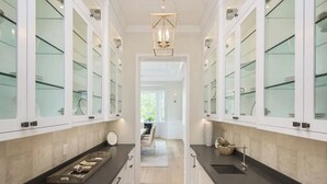 A modern kitchen with white cabinetry, black countertops, and a central island with a sink.