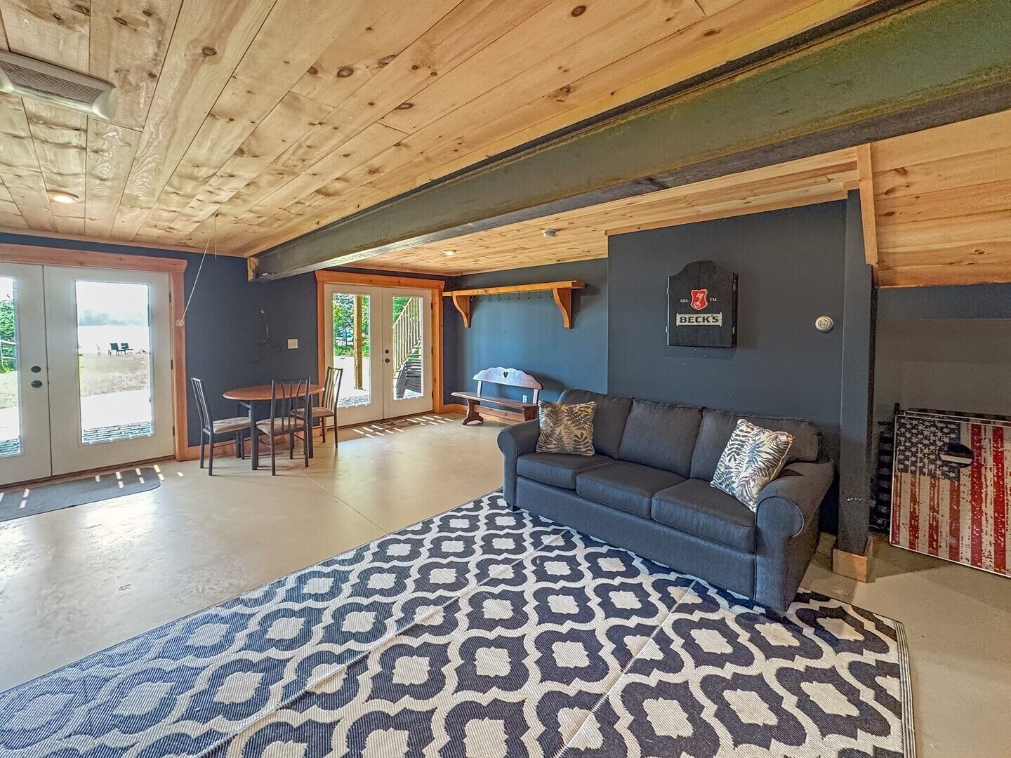 Un salon chaleureux avec un canapé bleu, un tapis à motifs et une cheminée décorée d’un drapeau américain.