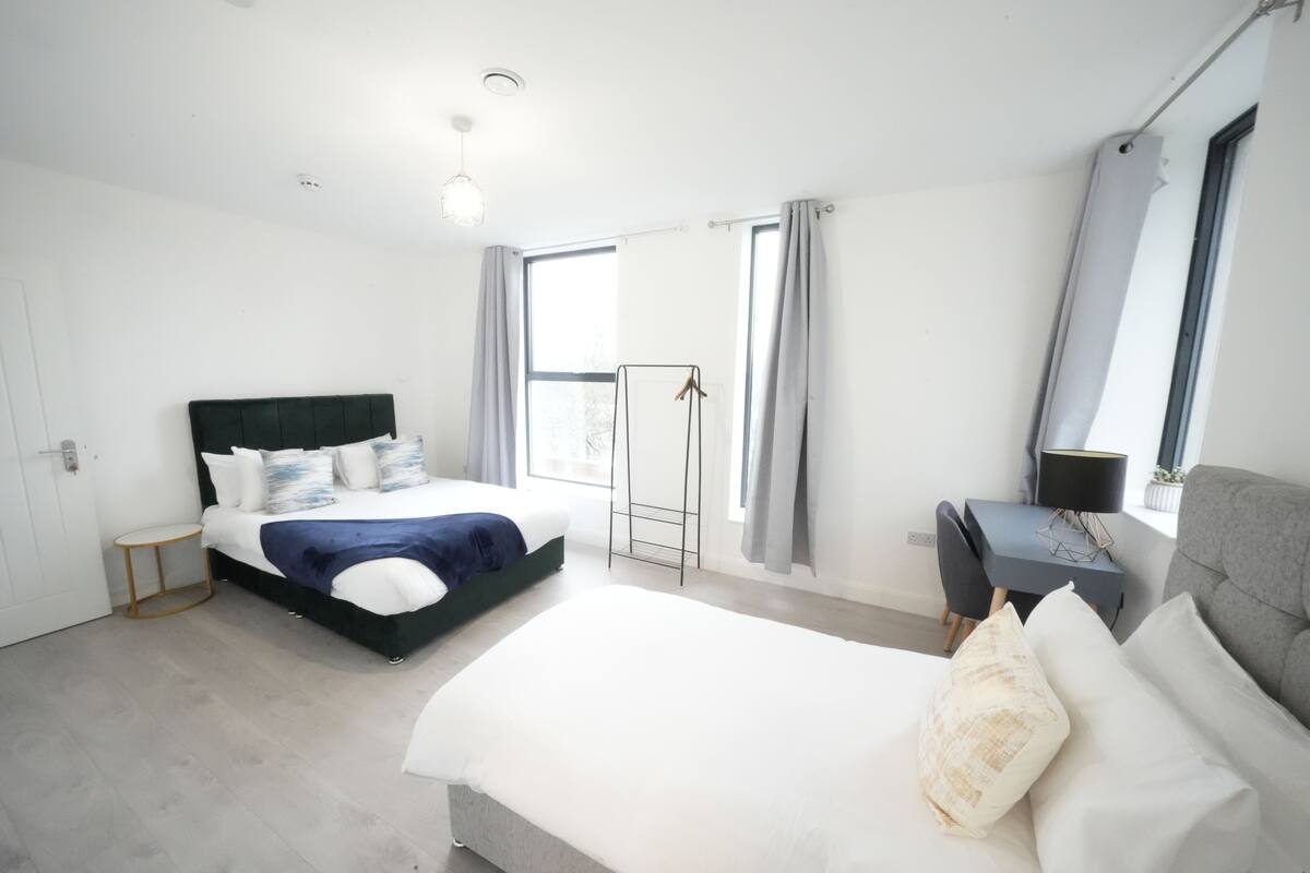 A modern bedroom with a large bed, a desk, and a chair.