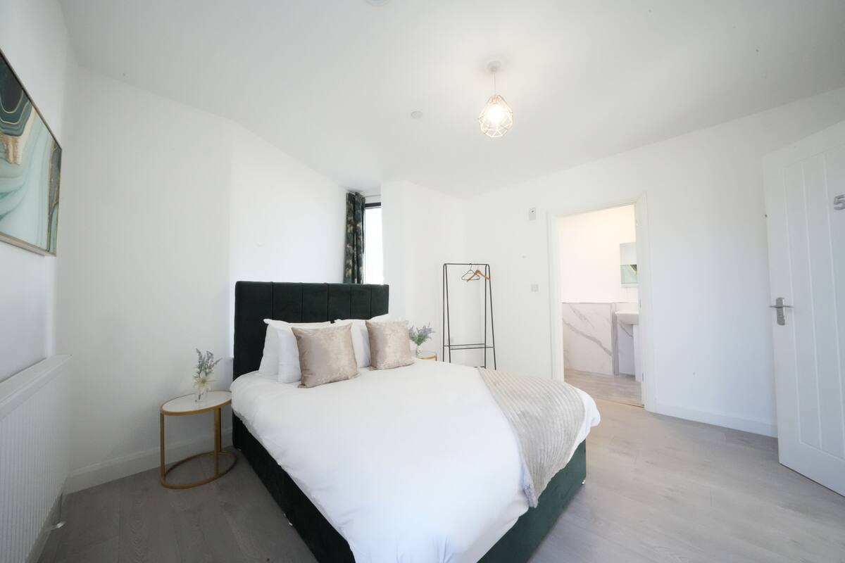 A modern bedroom with a large bed, a bedside table, and a hanging light fixture.