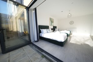A modern bedroom with a large bed, a sliding glass door, and a view of the outside. - Ealing Broadway Great Stay (London)
