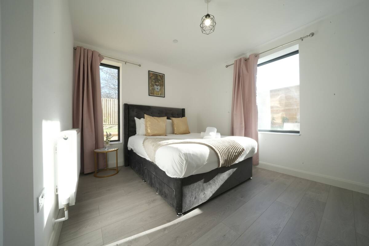 A bedroom with a bed, a small table, a radiator, and a window.