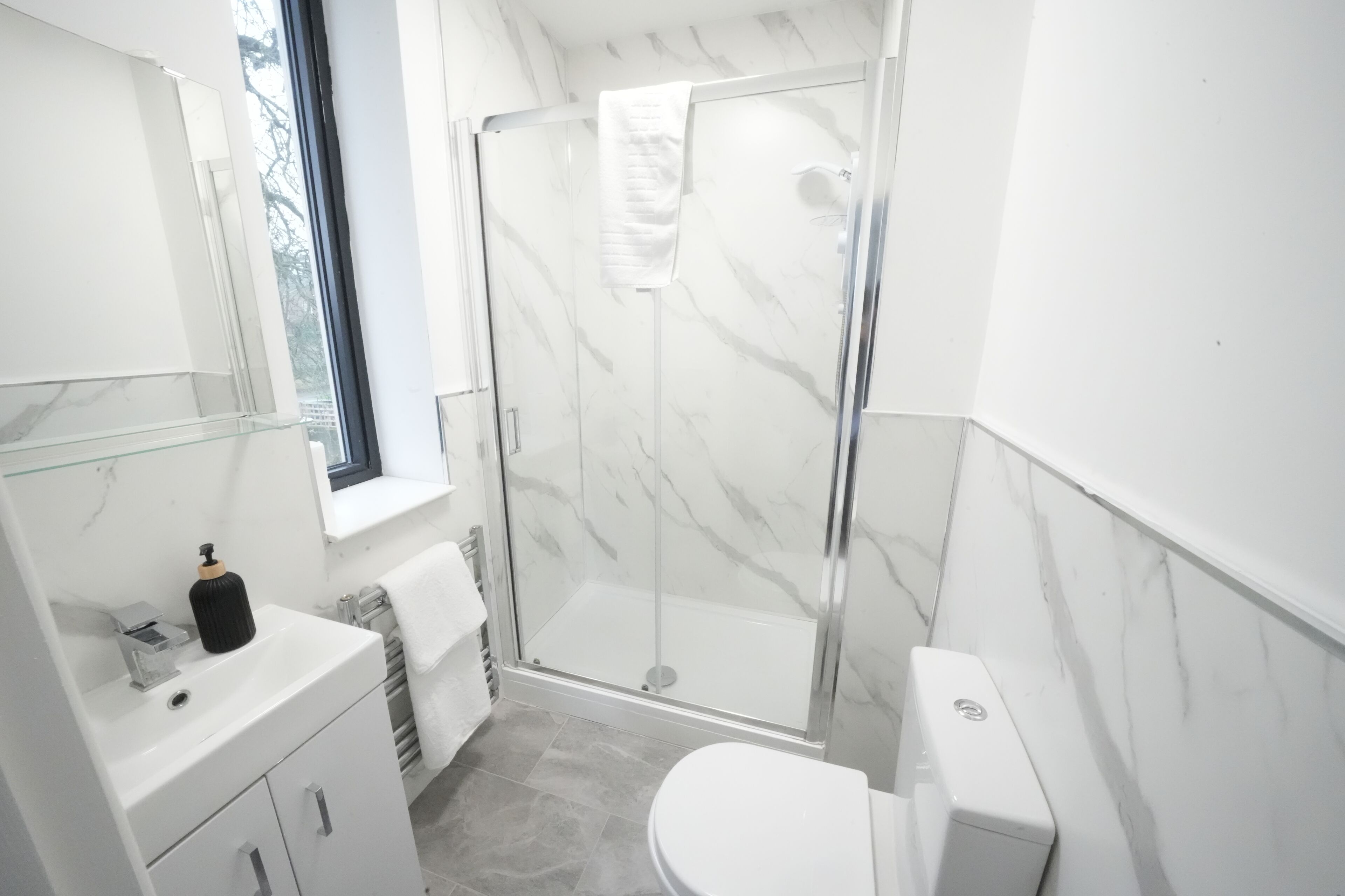 A modern bathroom with a glass shower enclosure, a white toilet, and a vanity with a mirror.