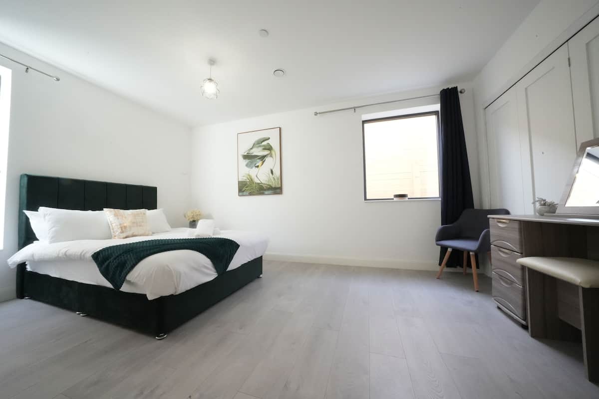 A bedroom with a bed, a dresser, a chair, and a window with curtains.