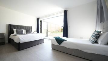Quarto de hotel moderno com duas camas, uma grande porta de vidro deslizante para o exterior e um design limpo e minimalista.