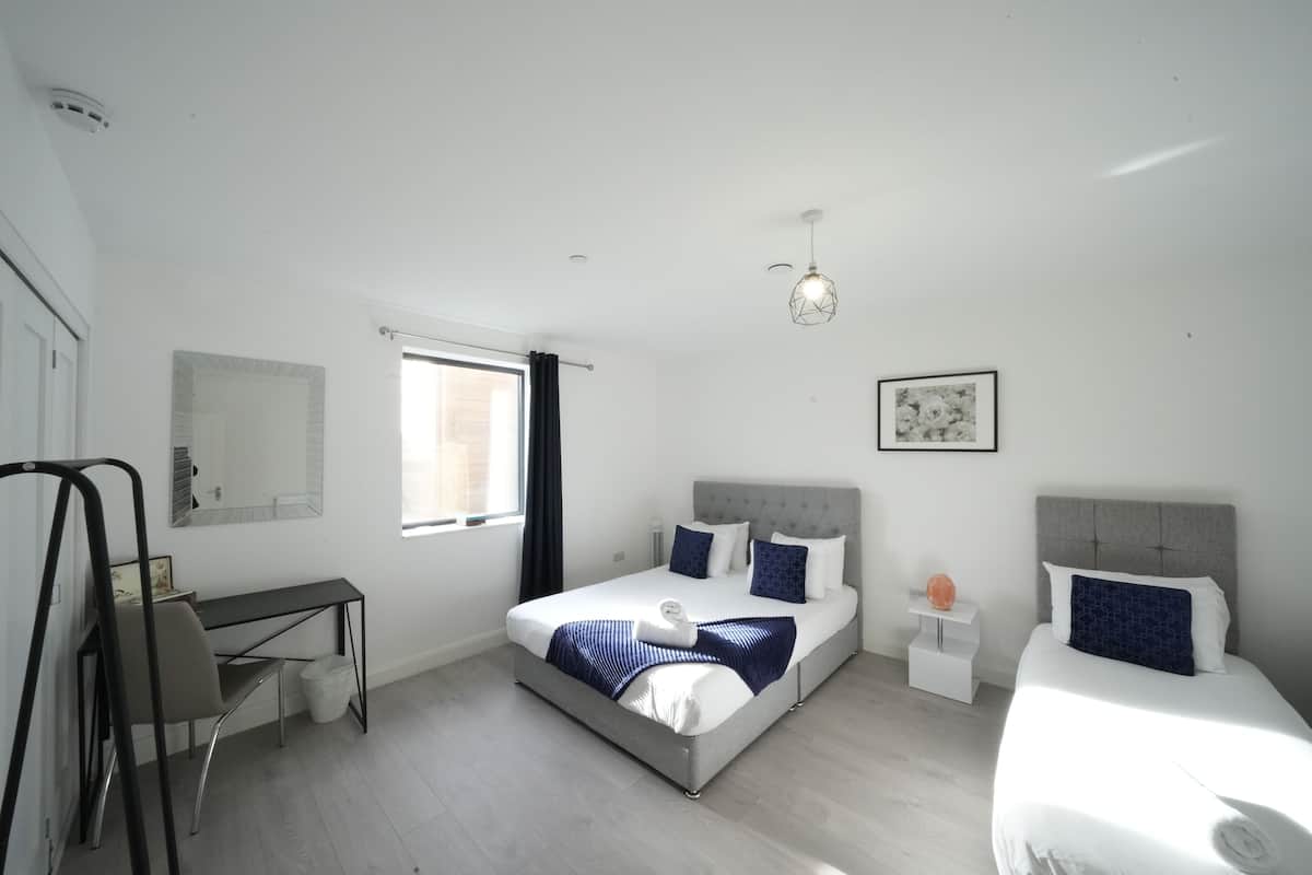 A modern bedroom with a bed, a desk, and a chair.