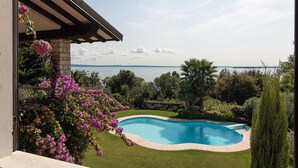 Une piscine à bord incurvé, entourée d’une pelouse bien entretenue et de plantes en fleurs.