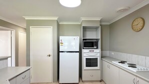 A compact kitchen with a refrigerator, microwave, oven, and stove. - Pelican Shore Villa 20 - Kalbarri WA (Kalbarri)