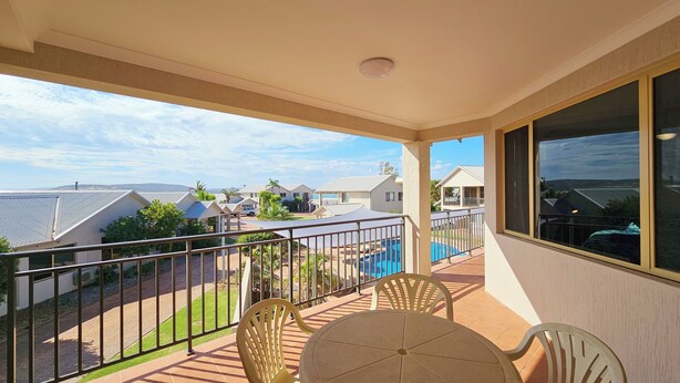 Un balcon donnant sur une piscine et les maisons voisines.